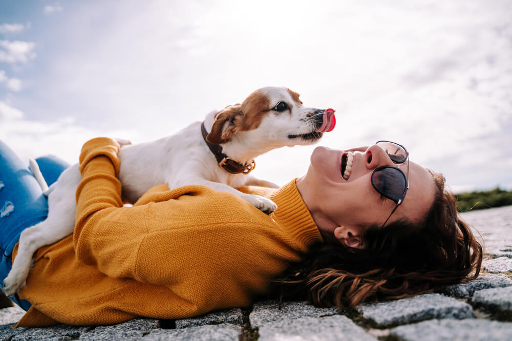 Frau kuschelt liegend mit Hund