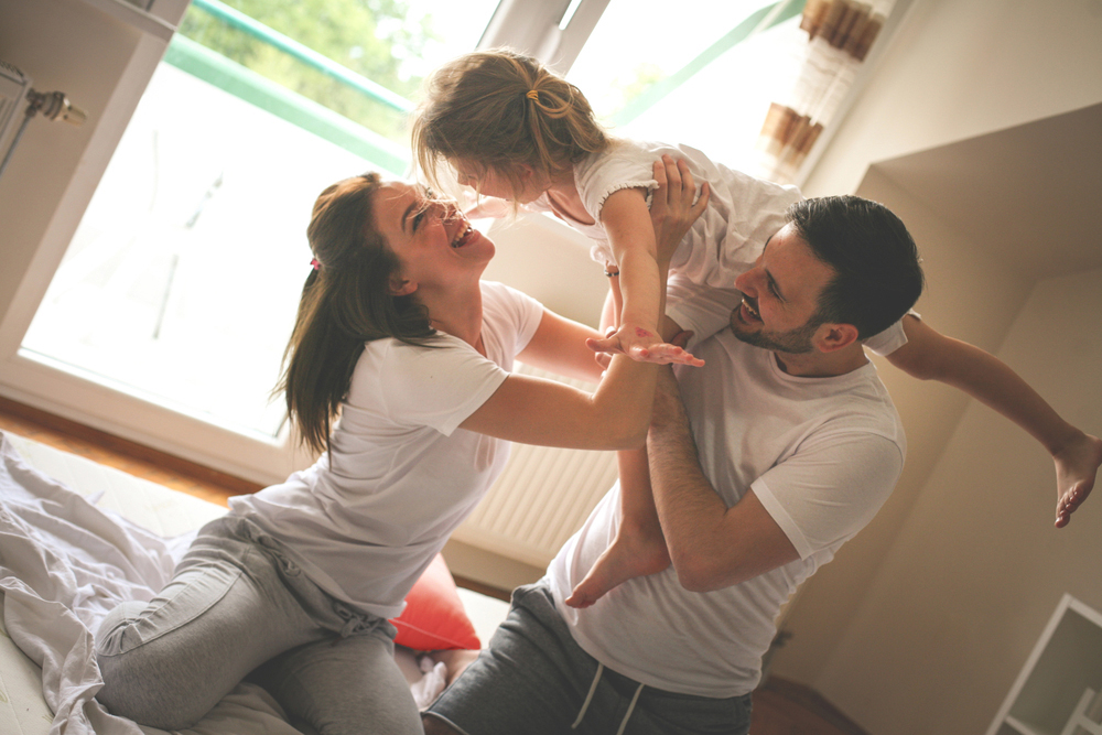 Mann und Frau spielen mit Mädchen im Wohnzimmer