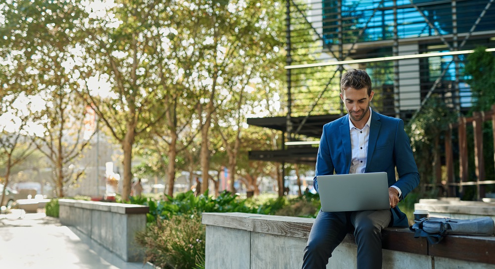 Mann mit Laptop vor modernem Gebäude