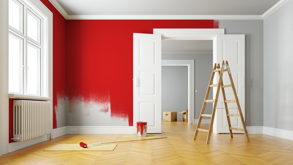 Streichen einer Wohnzimmerwand mit roter Farbe